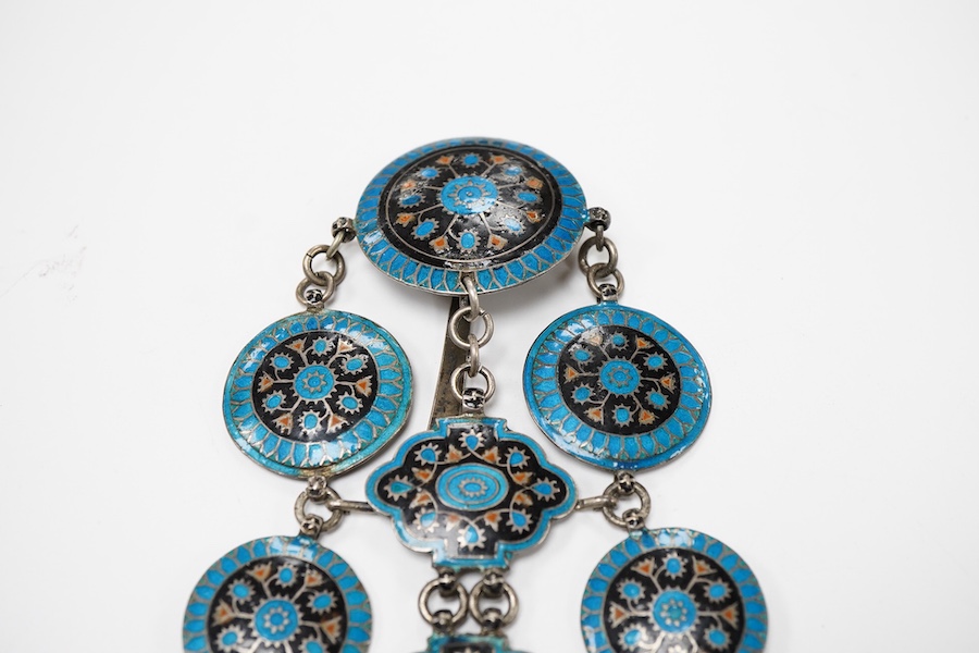 An enamel chatelaine, late 19th/early 20th century, composed of metal plaques applied with foliate patterns in blue, black and red enamel, indistinctly stamped maker's marks, suspending a silver pin cushion and a silver